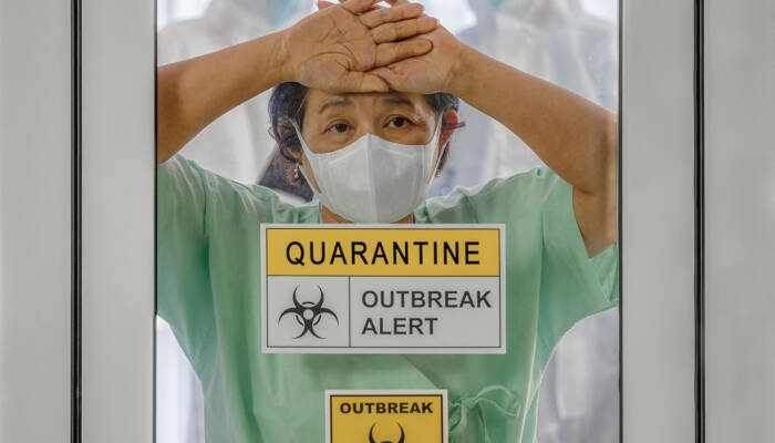 covid-19 infected patient in quarantine room with quarantine and breakout alert sign at hospital with blurred disease control experts inside